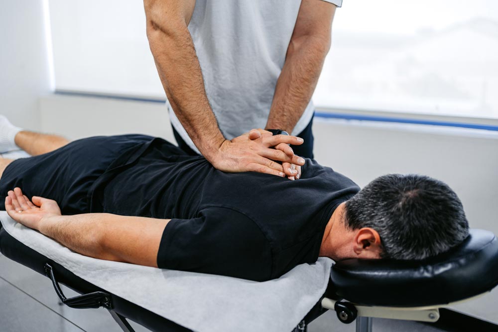 Therapist adjusting male client's upper back in his office