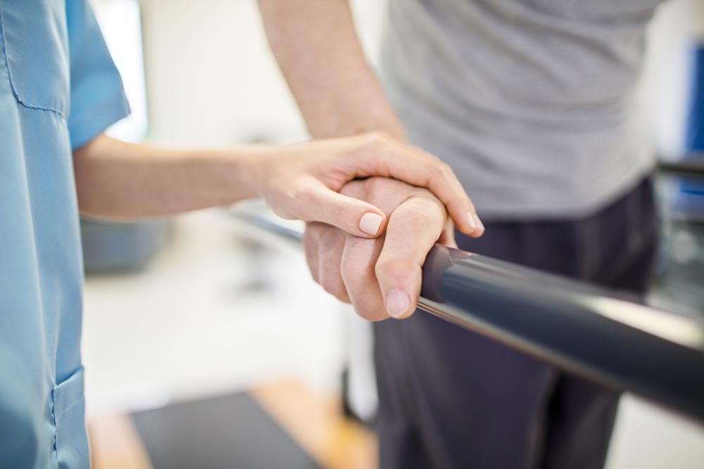 Female nurse touching senior man's hand on railing